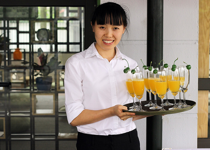 DERTOUR Foundation 10 Jahre KOTO Vietnam - Frau serviert Drinks